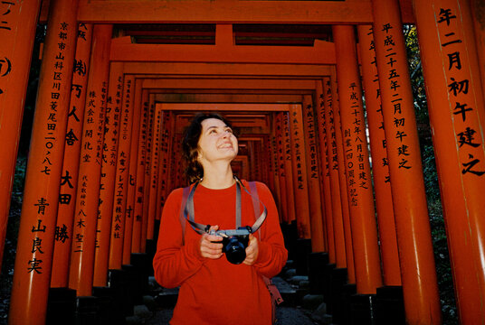 Woman walking through the tunnel of red torii gates in Kyoto