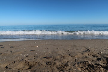 Scenic Ocean Waves Rolling onto Sandy Beach Under Clear Blue Sky