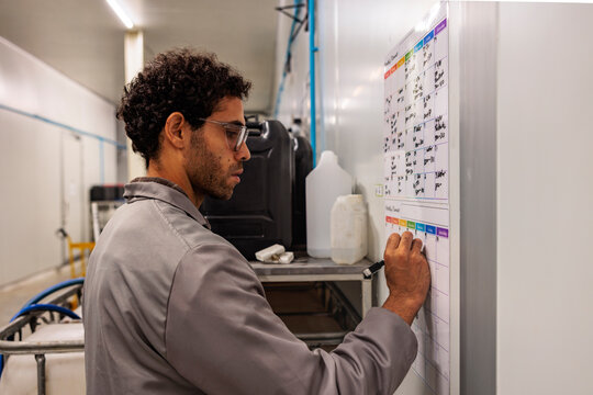 Man schedules tasks on a calendar in an industrial setting.