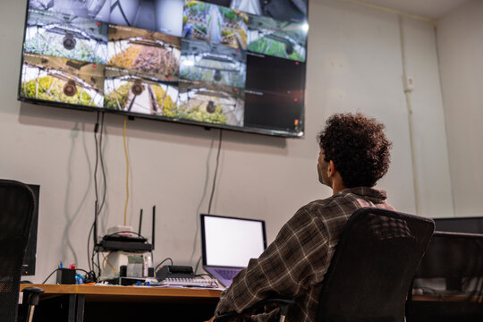 Man monitors security cameras in a bright, modern office.
