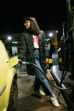 Woman Refueling Car at Night