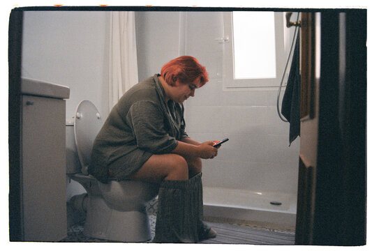 Woman sitting on toilet at home