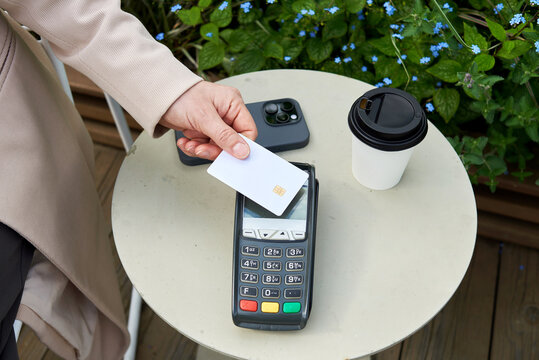 Woman using contactless payment at an outdoor cafe table