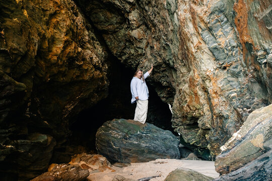 Person Exploring Rock Formations in a Cave on a Sunny Day