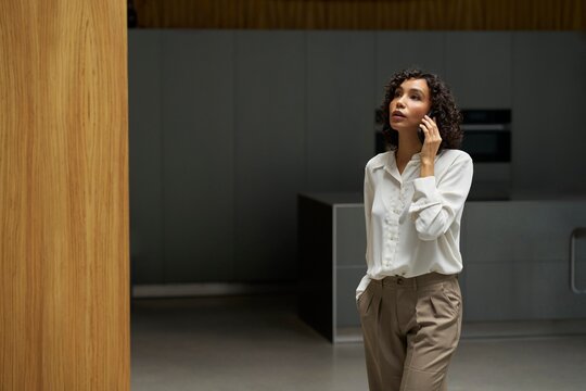 Woman Talking on Phone in Modern Office Setting During Daytime