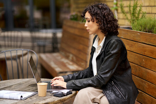 Gen Z professional working on laptop at outdoor cafe