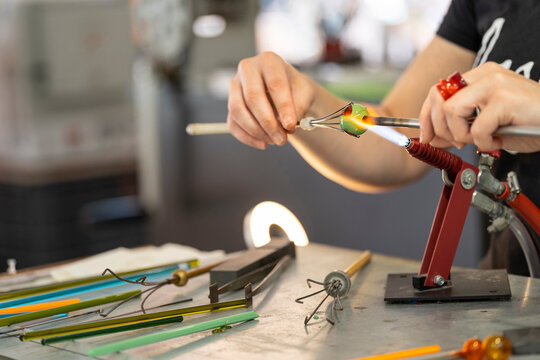 Close-up of the hands of a craftswoman making a piece of glass.
