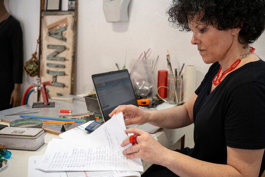 Business owner concentrating on looking at papers at a laptop