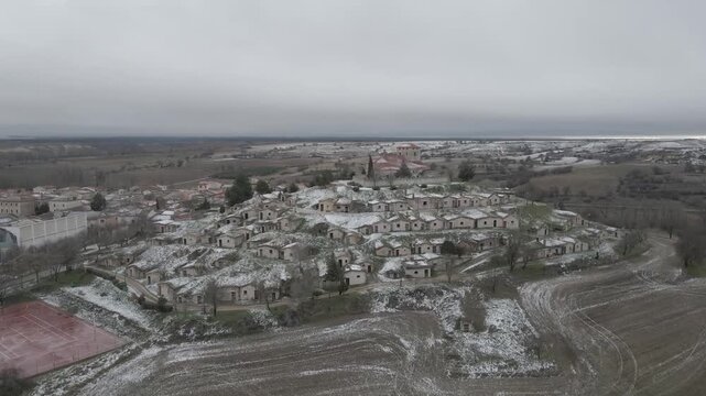 Aerial video approaching the snow-covered wineries of Moradillo de Roa, Spain.