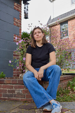 Woman sitting on a brick garden raised bed outside