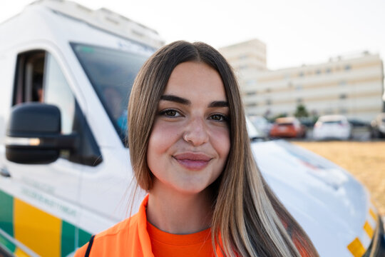 Paramedic smiling near ambulance in urban setting