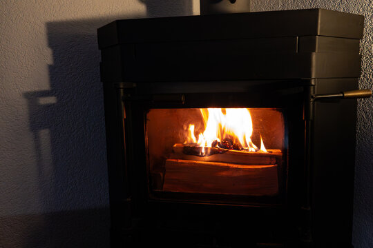 Firewood burning inside closed fireplace inset. 