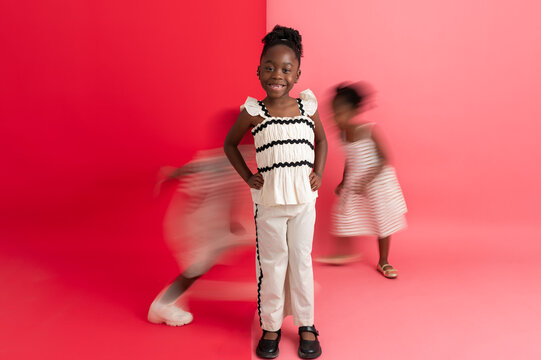 Big sister posing with siblings running behind her
