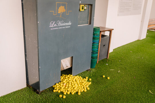 Golf ball collection machine at La Hacienda Golf Resort with yellow balls scattered on green turf and blue stacking containers nearby