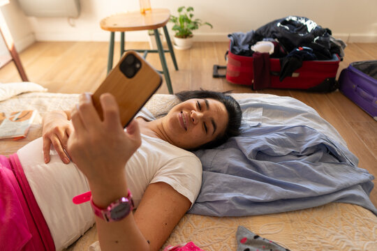 Woman Laying on Bed Taking Selfie in Casual Setting