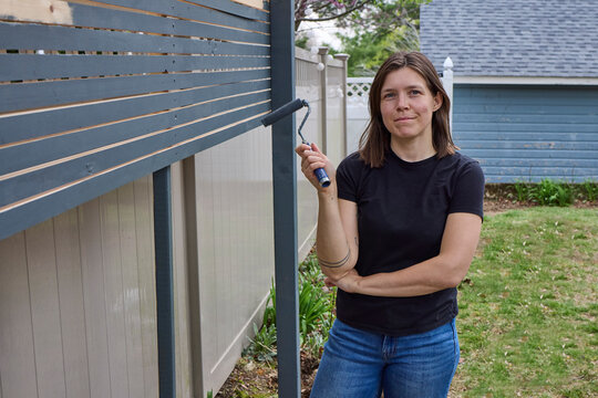Woman painting a fence outside dark