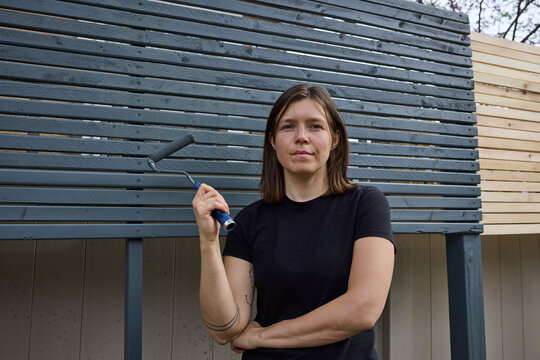 Woman painting a fence outside dark