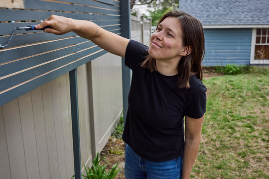 Woman painting a fence outside dark