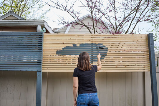 Woman painting a fence outside dark