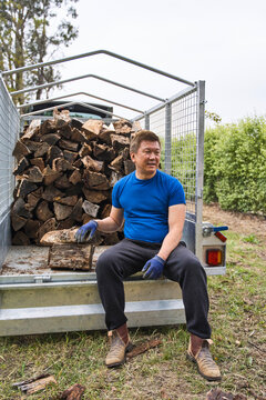 Man Resting on Trailer After Unloading Firewood in the Countryside
