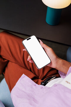 Person holds  Phone with White Screen in Casual Workspace Mockup