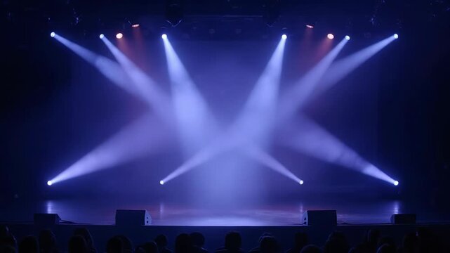 Stage lights illuminate an empty theater with dramatic blue beams. The performance space awaits its audience and performers.