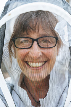 Closeup of smiling beekeeper behind mesh veil