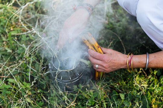 Hands lighting a bee smoker in grass