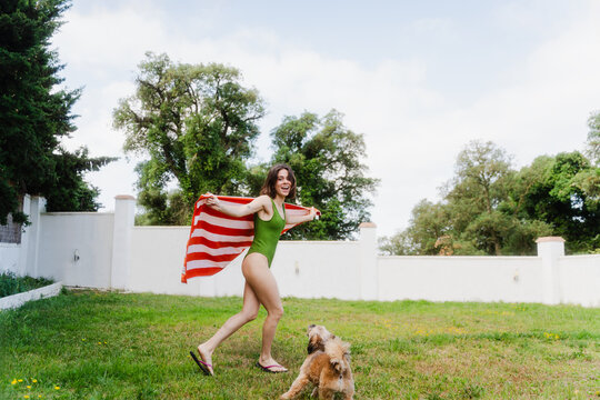 Woman in a swimsuit plays with her dog