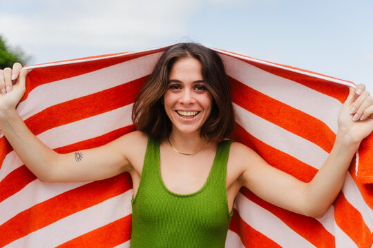 Joyful woman displays a beach towel laid out