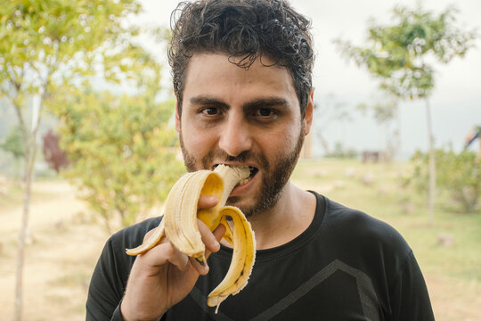 Young man enjoys banana in a natural outdoor setting
