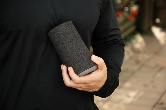 Man holding a portable speaker in a casual outdoor setting