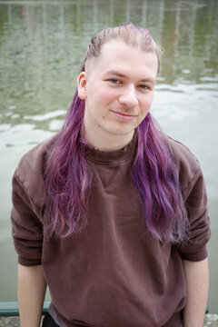 Portrait of a smiling man with long hair near a river