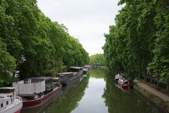 Boats Lined Along a Canal Surrounded by Lush Trees