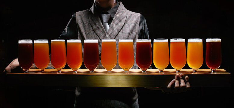 A bartender holding a one-meter-long beer tray stands against  