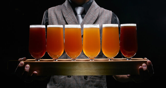 A bartender holding a craft beer jug ​​half a meter long stands agains