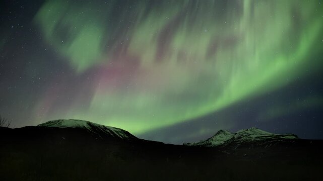 Red and green pulsating aurora borealis over snowy peaks Iceland