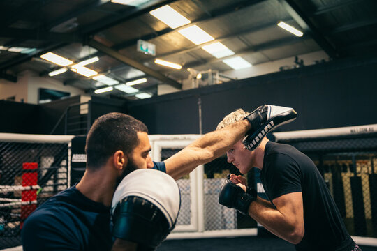 MMA practice with a coach in a boxing ring
