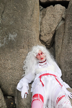 A woman in a wig and a  bright costume walks in the park