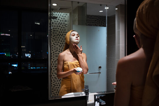 Woman Applying Facial Mask in Hotel Bathroom During Evening