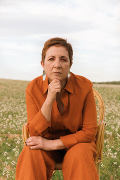 Woman sitting in a field with thoughtful expression during daytime