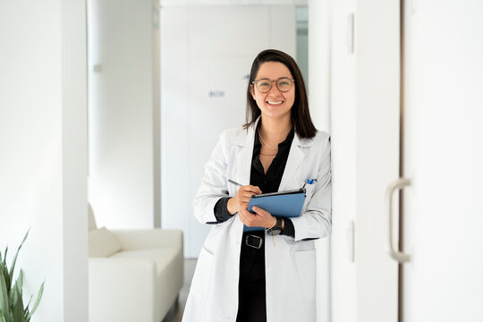 Female doctor smiling and taking notes on a clipboard in a hospital