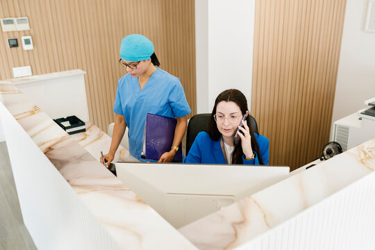 Receptionist talking on phone and nurse writing at dental