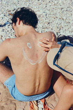 Woman drawing a smile face in her boyfriend's back with sunscreen