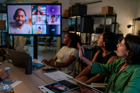 Team meeting with remote participants on large screen at night