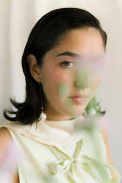 Young woman posing gracefully with flowers in soft focus