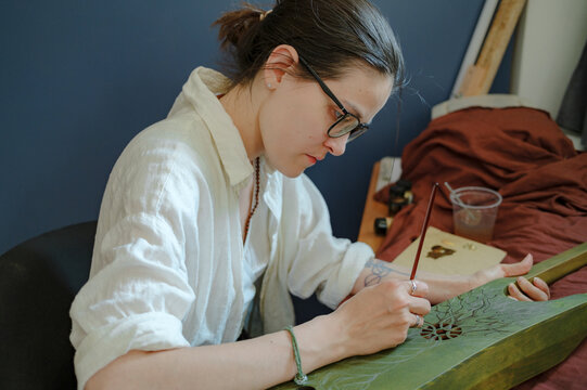 A woman paints a musical instrument