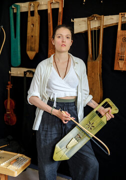 portrait of a woman in a workshop with musical instruments in the back