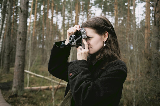 Girl using vintage camera in a forest setting during early spring