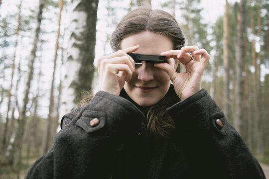 Girl holding a retro camera in a forest during early spring
